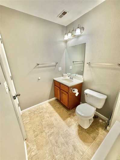 Bathroom with toilet, vanity, visible vents, and baseboards
