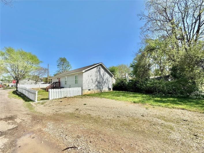 View of side of home with driveway, crawl space, and a fenced front yard