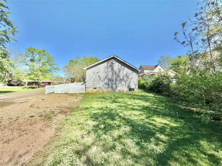 View of side of property featuring a yard, crawl space, and fence