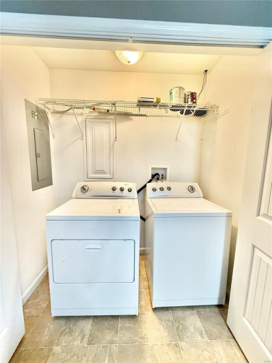 Laundry room featuring electric panel, washing machine and clothes dryer, baseboards, and laundry area