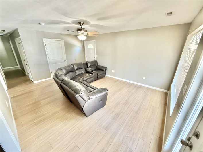 Living area with light wood-type flooring, baseboards, visible vents, and ceiling fan