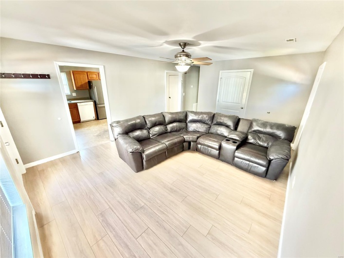 Living area featuring visible vents, light wood finished floors, baseboards, and ceiling fan