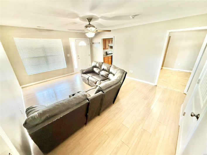 Living area with light wood finished floors, baseboards, and ceiling fan