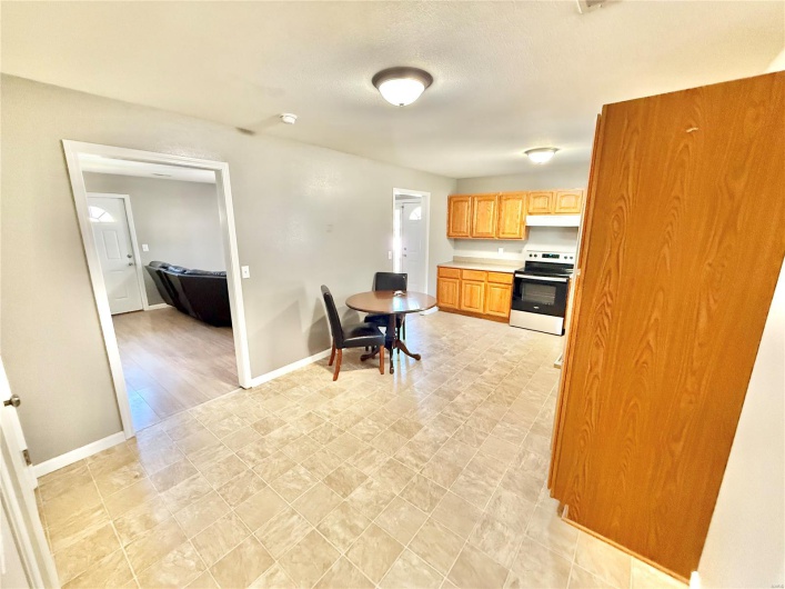Kitchen with baseboards, light countertops, under cabinet range hood, and electric range oven