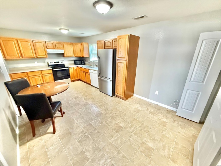 Kitchen with stainless steel appliances, a sink, baseboards, light countertops, and under cabinet range hood