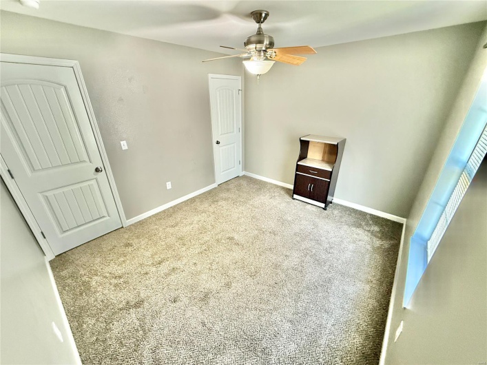 Unfurnished bedroom with ceiling fan, carpet floors, and baseboards