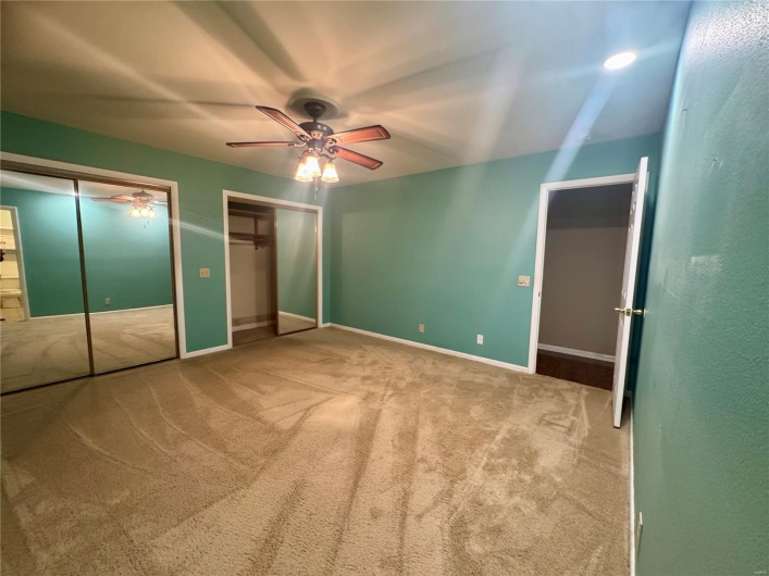Unfurnished bedroom with carpet floors, multiple closets, ceiling fan, and baseboards