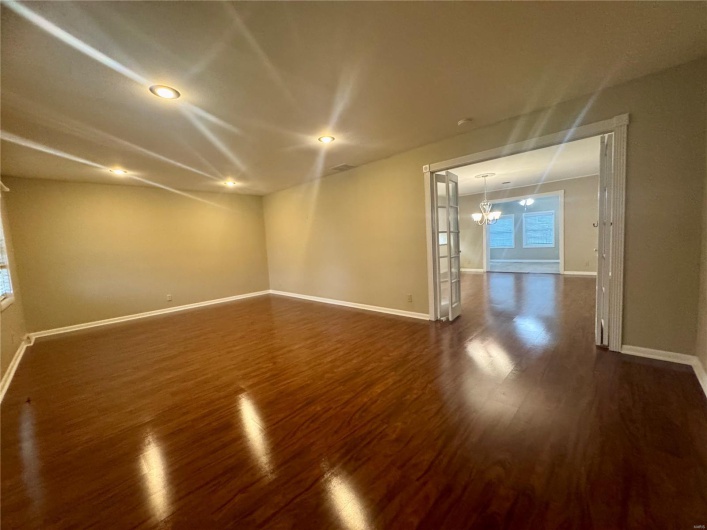 Spare room with baseboards, recessed lighting, wood finished floors, and a chandelier