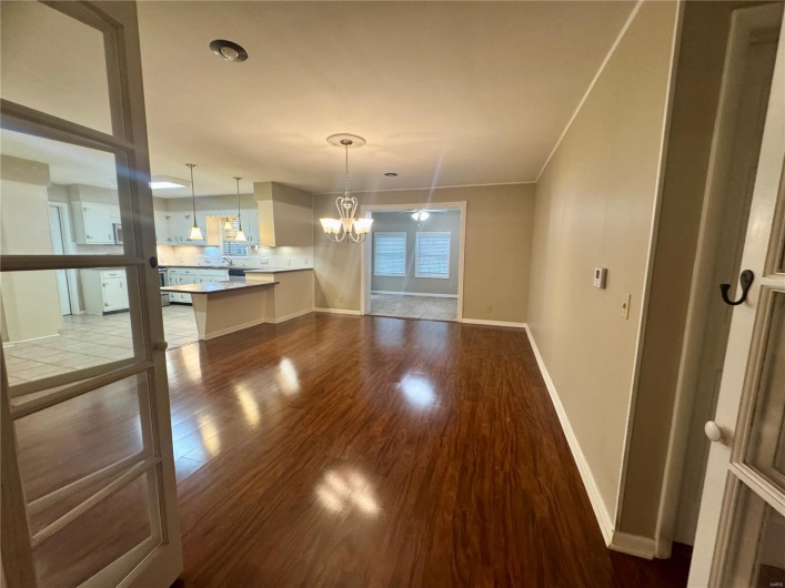 Unfurnished dining area with baseboards, an inviting chandelier, and dark wood-type flooring