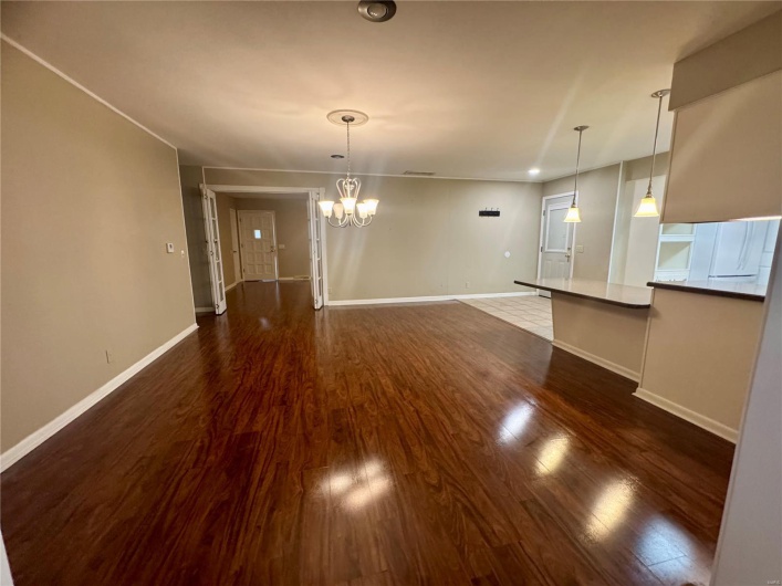 baseboards, dark wood-type flooring, and a chandelier