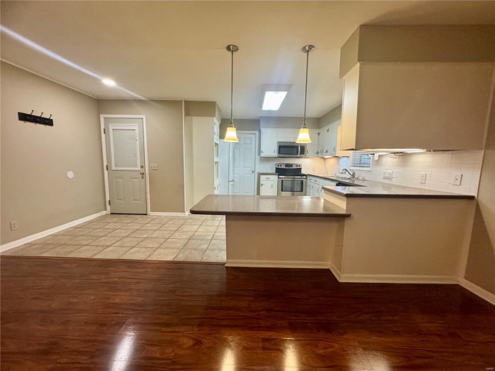 Kitchen featuring a sink, light wood finished floors, stainless steel appliances, a peninsula, and tasteful backsplash