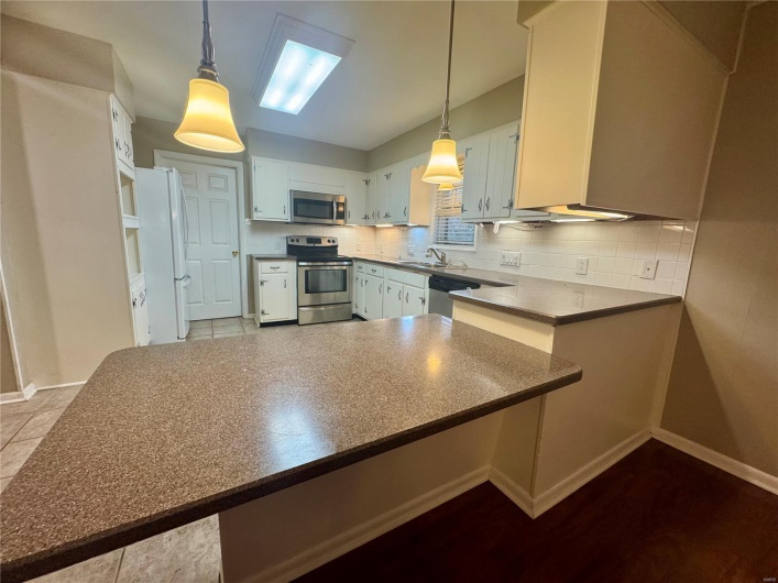 Kitchen featuring baseboards, appliances with stainless steel finishes, decorative backsplash, and a sink