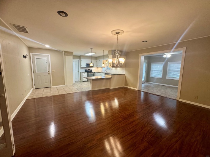 Unfurnished dining area with baseboards, an inviting chandelier, light wood-style flooring, and visible vents