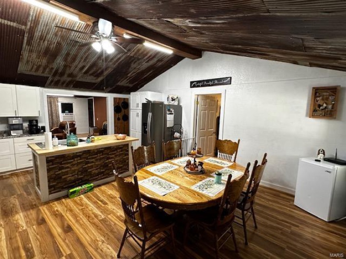Dining space featuring lofted ceiling with beams, ceiling fan, wooden ceiling, and dark hardwood / wood-style flooring