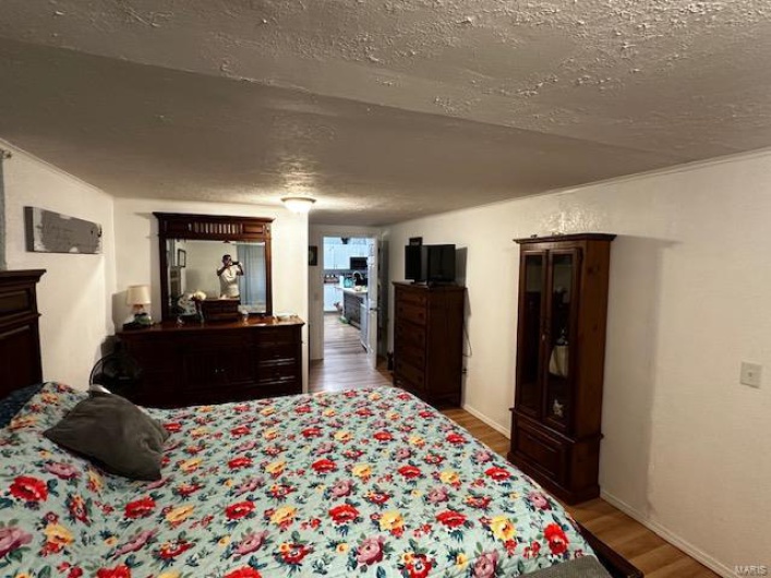 Bedroom with hardwood / wood-style flooring and a textured ceiling