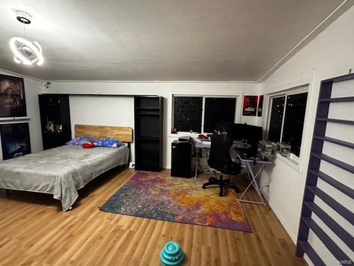 Bedroom featuring vaulted ceiling, hardwood / wood-style flooring, and ornamental molding