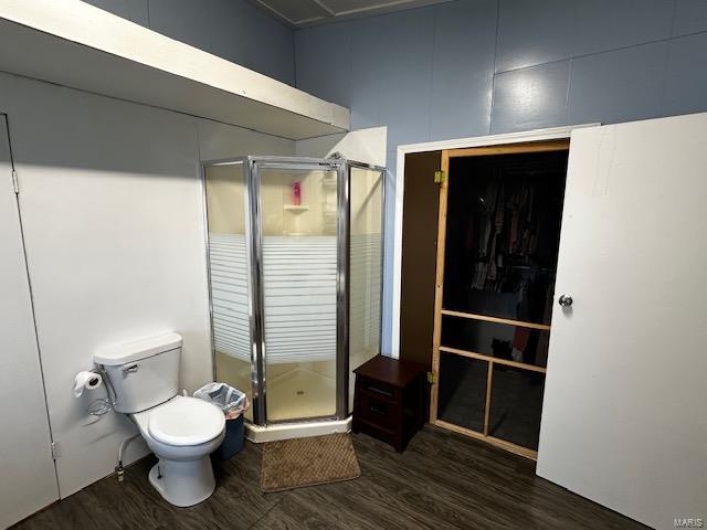 Bathroom with a shower with door, toilet, and wood-type flooring