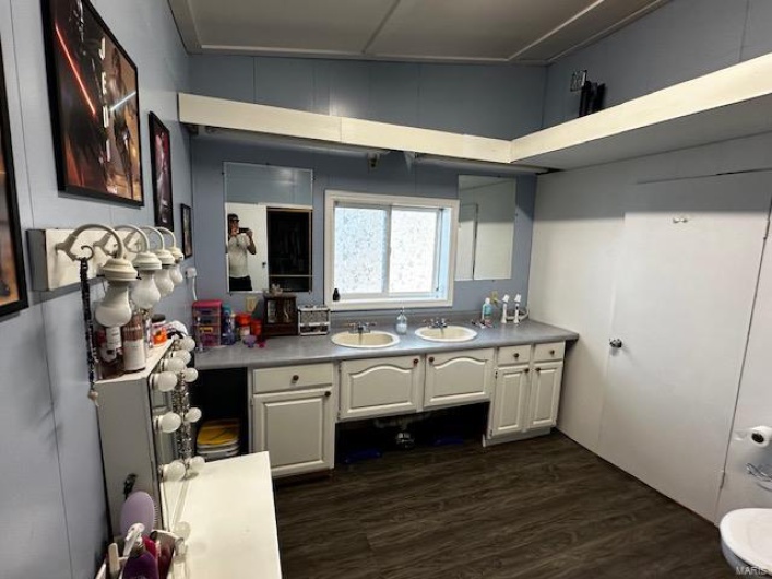 Kitchen with dark wood-type flooring, sink, and white cabinets