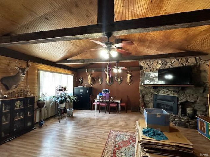 Living room with lofted ceiling with beams, a fireplace, hardwood / wood-style floors, and wooden ceiling