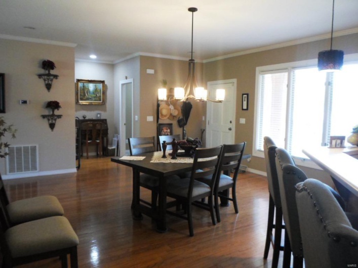 Dining room with dark wood-style floors, visible vents, ornamental molding, baseboards, and a chandelier