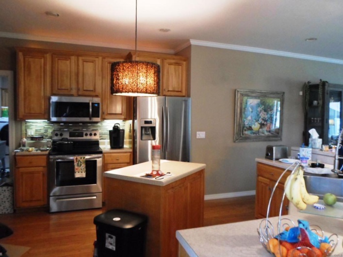 Kitchen featuring a center island, light countertops, appliances with stainless steel finishes, and dark wood finished floors