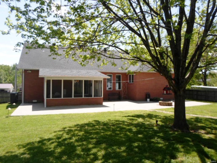Back of property featuring fence, a lawn, a sunroom, and a patio
