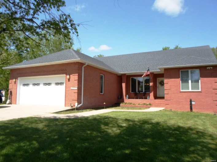 Single story home with an attached garage, driveway, brick siding, and a front yard
