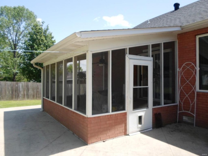 View of home's exterior featuring brick siding, a sunroom, fence, and roof with shingles