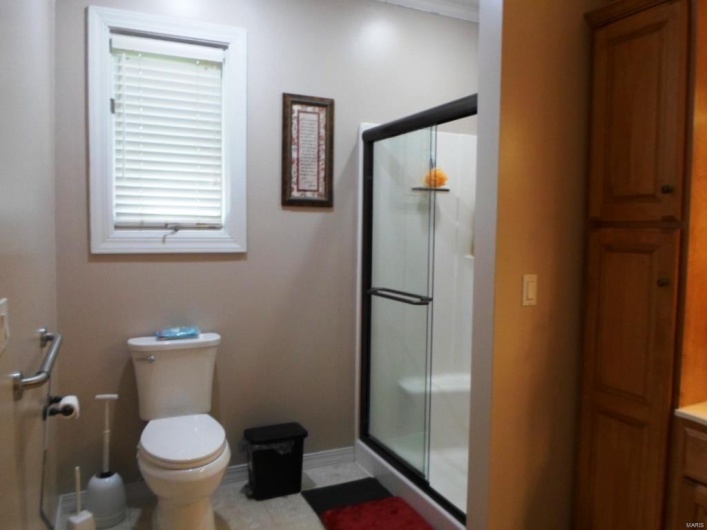 Full bath featuring toilet, baseboards, and a stall shower