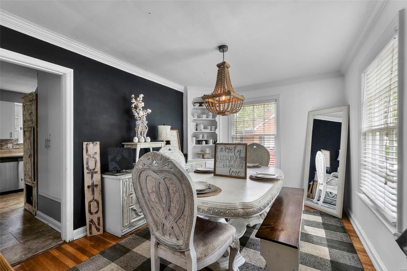Dining room with a chandelier, wood finished floors, baseboards, and ornamental molding