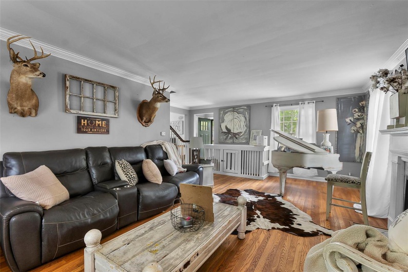 Living room featuring stairway, crown molding, wood finished floors, and a fireplace