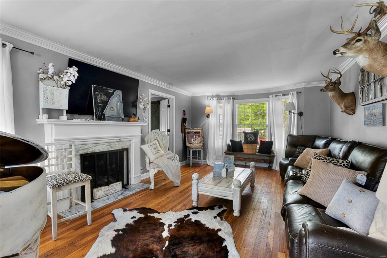 Living room with wood-type flooring, crown molding, and a fireplace