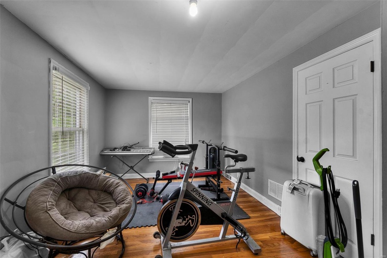 Workout room with wood finished floors, visible vents, and baseboards