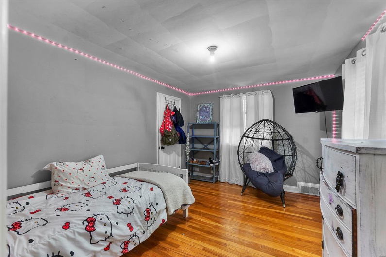 Bedroom with wood finished floors, visible vents, and baseboards