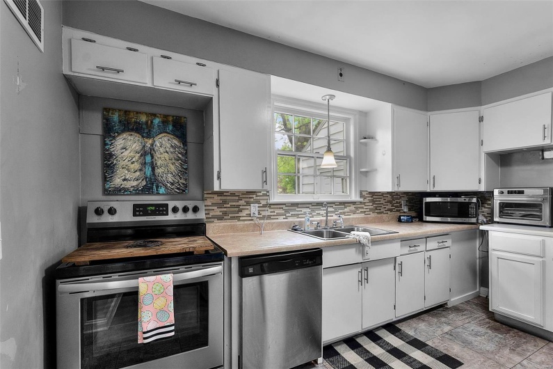 Kitchen featuring a sink, visible vents, white cabinetry, light countertops, and appliances with stainless steel finishes