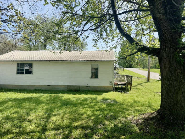 View of side of home with crawl space, a yard, and metal roof