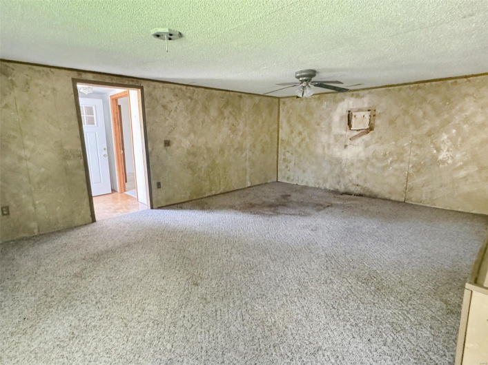Carpeted empty room featuring a ceiling fan