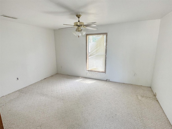 Carpeted spare room with a ceiling fan and visible vents