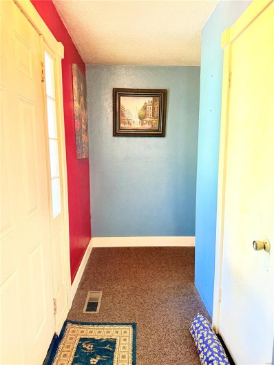Hallway with carpet floors, a textured ceiling, visible vents, and baseboards