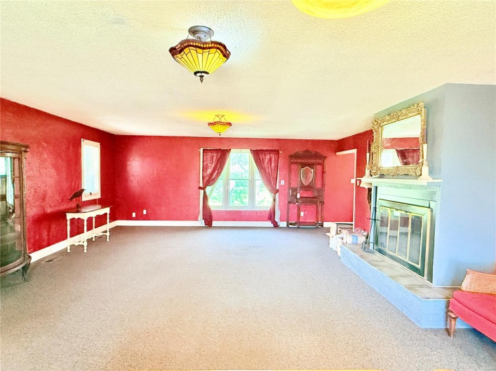 Unfurnished room with baseboards, a glass covered fireplace, a textured ceiling, and carpet