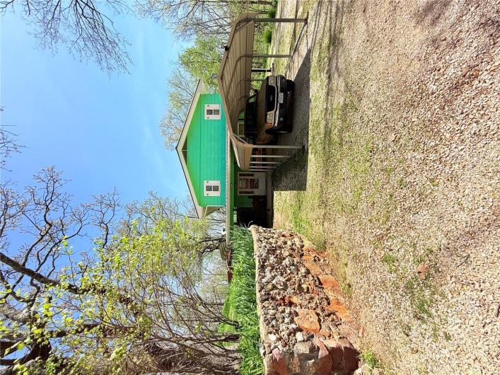 View of property exterior featuring dirt driveway and a detached carport