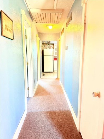 Hallway featuring light colored carpet and visible vents