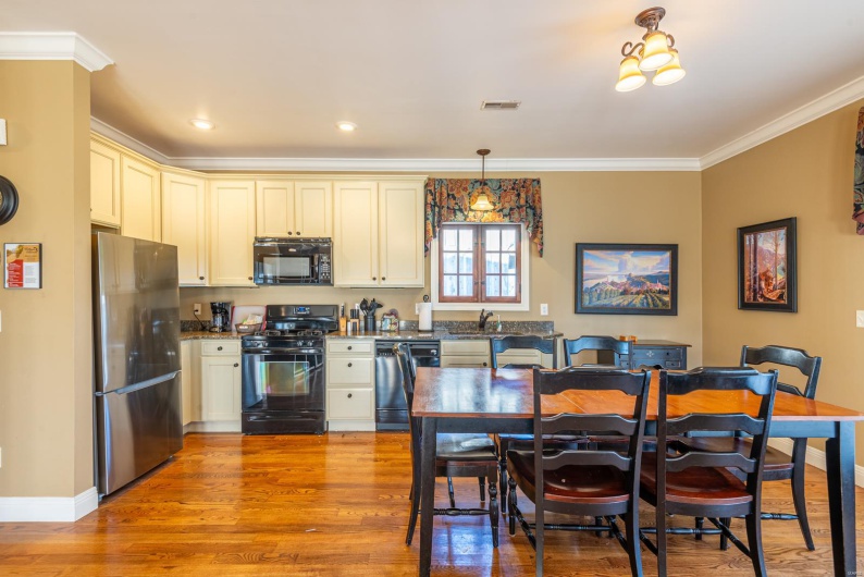 Kitchen with black appliances, sink, light wood-type flooring, ornamental molding, and decorative light fixtures