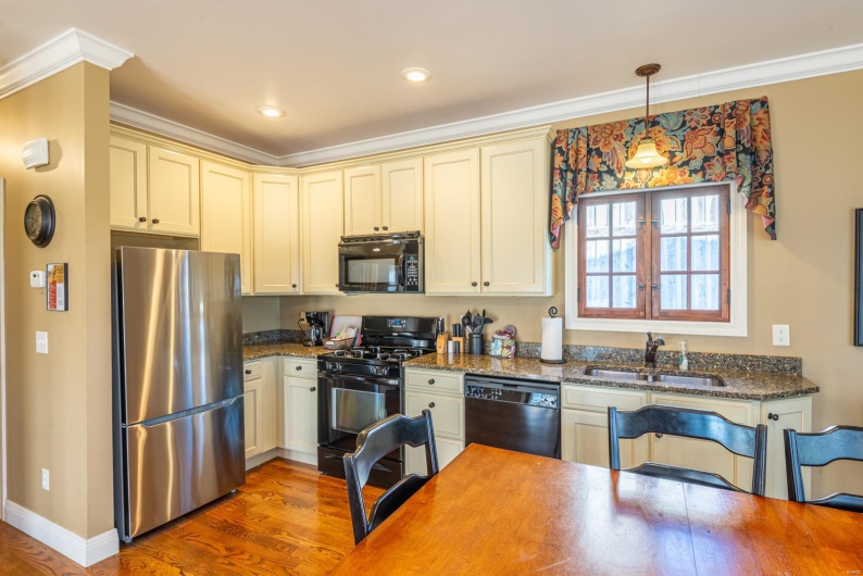 Kitchen featuring dark wood-type flooring, sink, black appliances, and decorative light fixtures