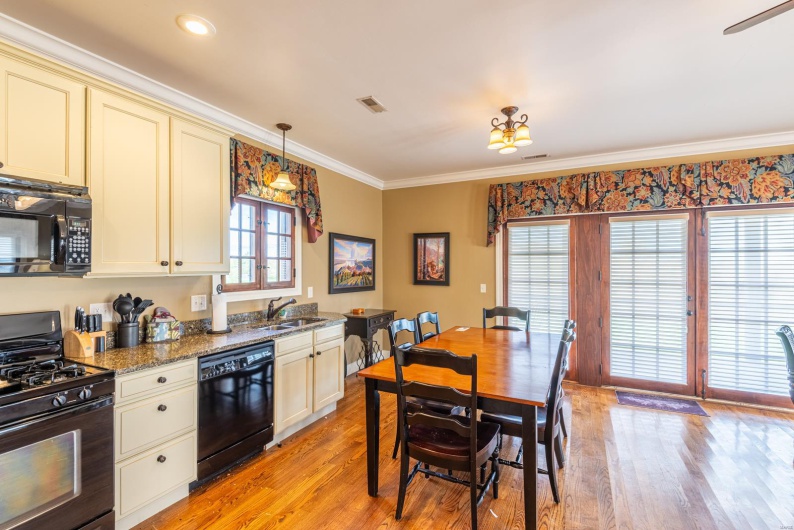 Kitchen with sink, cream cabinets, dark stone counters, pendant lighting, and black appliances