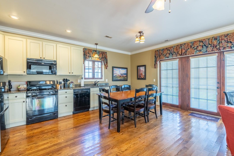 Kitchen featuring cream cabinets, black appliances, light hardwood / wood-style flooring, ornamental molding, and decorative light fixtures