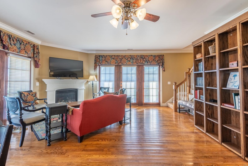 Living room featuring ceiling fan, wood-type flooring, and crown molding