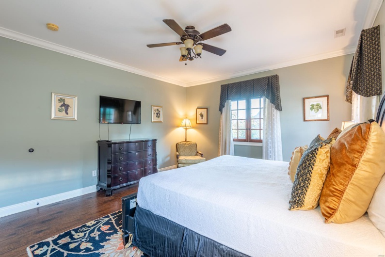 Bedroom featuring dark hardwood / wood-style flooring, ceiling fan, and crown molding