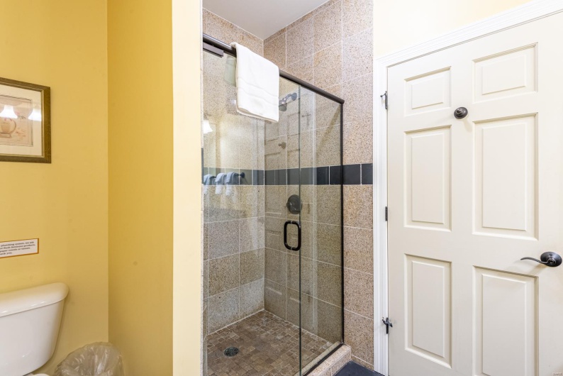 Bathroom featuring a shower with door and toilet