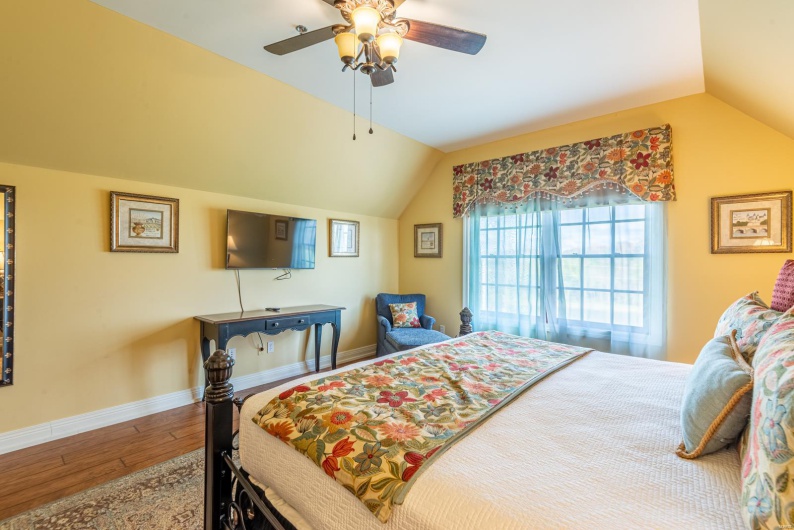 Bedroom featuring hardwood / wood-style flooring, ceiling fan, and vaulted ceiling